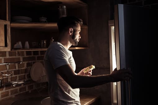 young man looking for something to eat in refrigerator